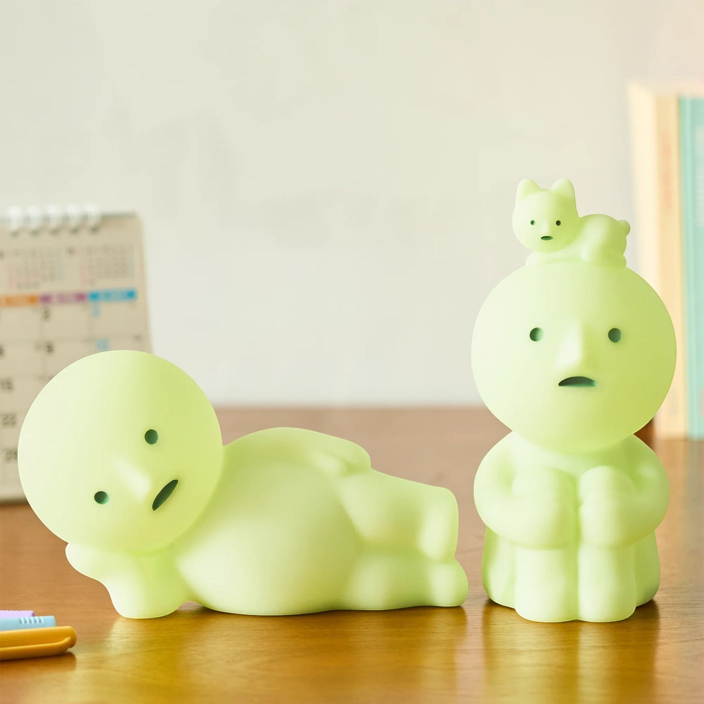 Smiski Touch Light lounging figure and standing figure, both light green, on tabletop