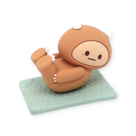Brown Smoko Hank Yeti figure doing a yoga boat pose on a textured pale green yoga mat against white background