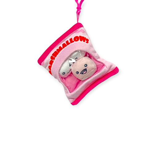 Introducing Bensons' Snack Bites Bag Charm: a delightful toy shaped like a pink and white marshmallow bag. Inside, find two smiling plush marshmallows with cartoon faces and a handy pink strap on top. Perfect for plush snack lovers!.