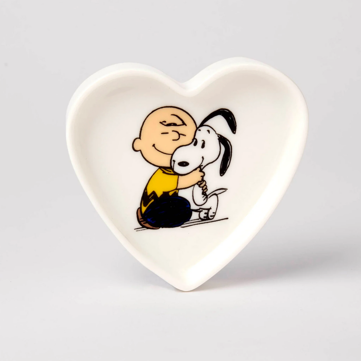 White heart-shaped ceramic dish with Snoopy and Charlie Brown illustration