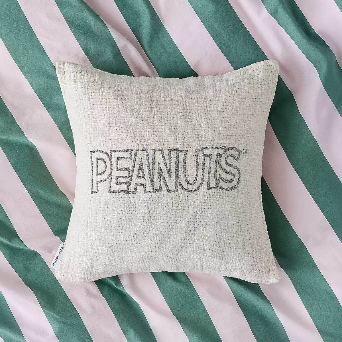 Cream cotton cushion cover with PEANUTS logo centered on front