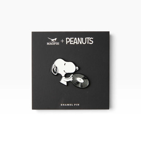Enamel pin of Snoopy holding a vinyl record on a display card