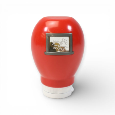 Red condiment bottle with small framed mirror reflecting faint cursive text on smooth white background