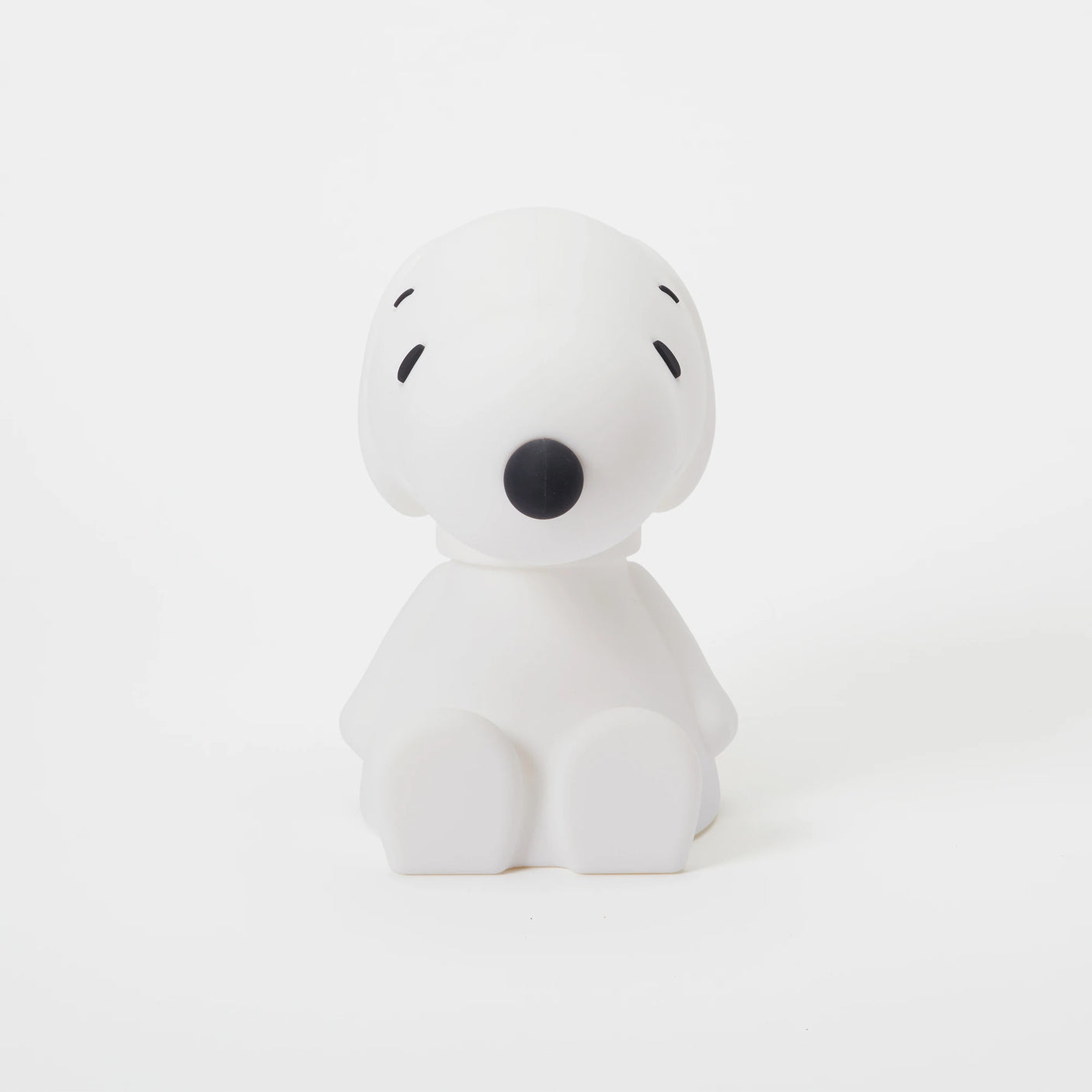 A charming white figurine with a round head and small black features, reminiscent of a cartoon character, sits against a plain background. This delightful piece suggests the design of the Snoopy Night Light (11cm) by Snoopy, crafted from BPA-free silicone for your safety and comfort.