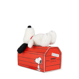 The Snoopy Plush Doghouse Gift Set - 17cm by Snoopy showcases a delightful white dog with black ears lounging on a red doghouse, adorned with an enchanting cartoon design. It's a perfect addition to any Peanuts Magic collection and makes an ideal gift set for fans of all ages.