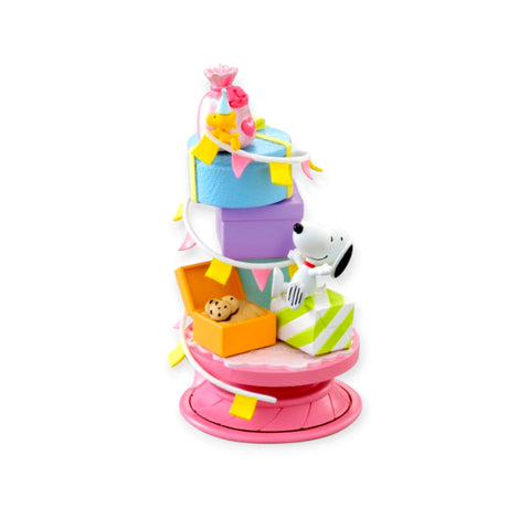 Spiral diorama featuring Snoopy and Woodstock with colorful gift boxes, cookies, and festive flags on rotating pink base