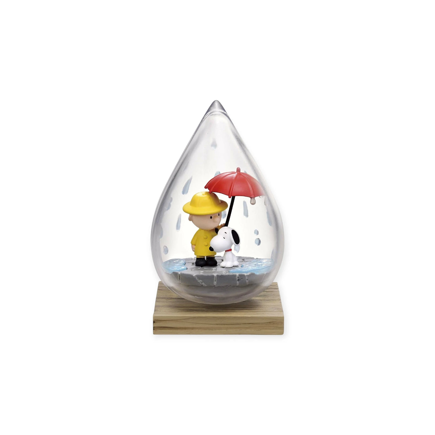 Enclosed within a raindrop-shaped glass dome, the Snoopy Blind Box - Weather Terrarium by Re-Ment features a delightful figurine of a character in a yellow raincoat with a red umbrella standing alongside Snoopy, perfectly capturing the charming essence of the Peanuts Collection.