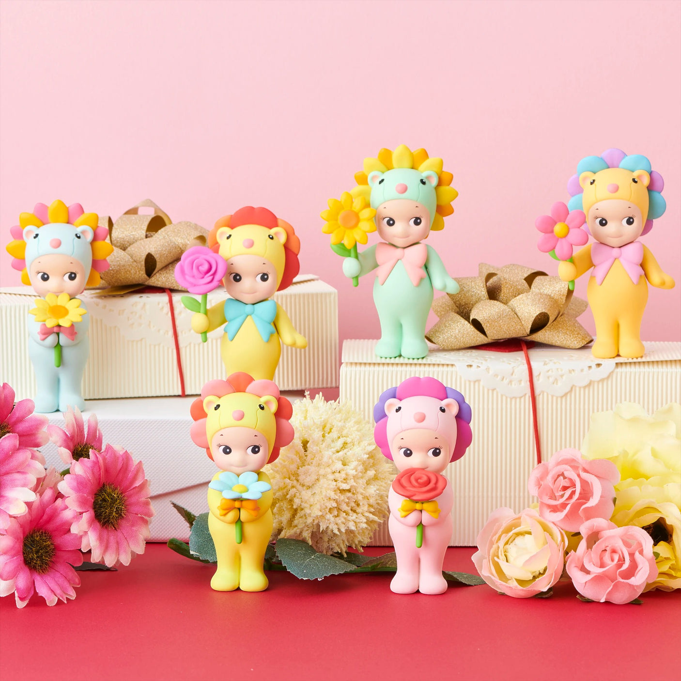 Assorted flower-themed mini figures arranged with gift boxes and pink and white flowers