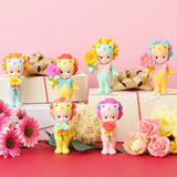 Assorted flower-themed mini figures arranged with gift boxes and pink and white flowers