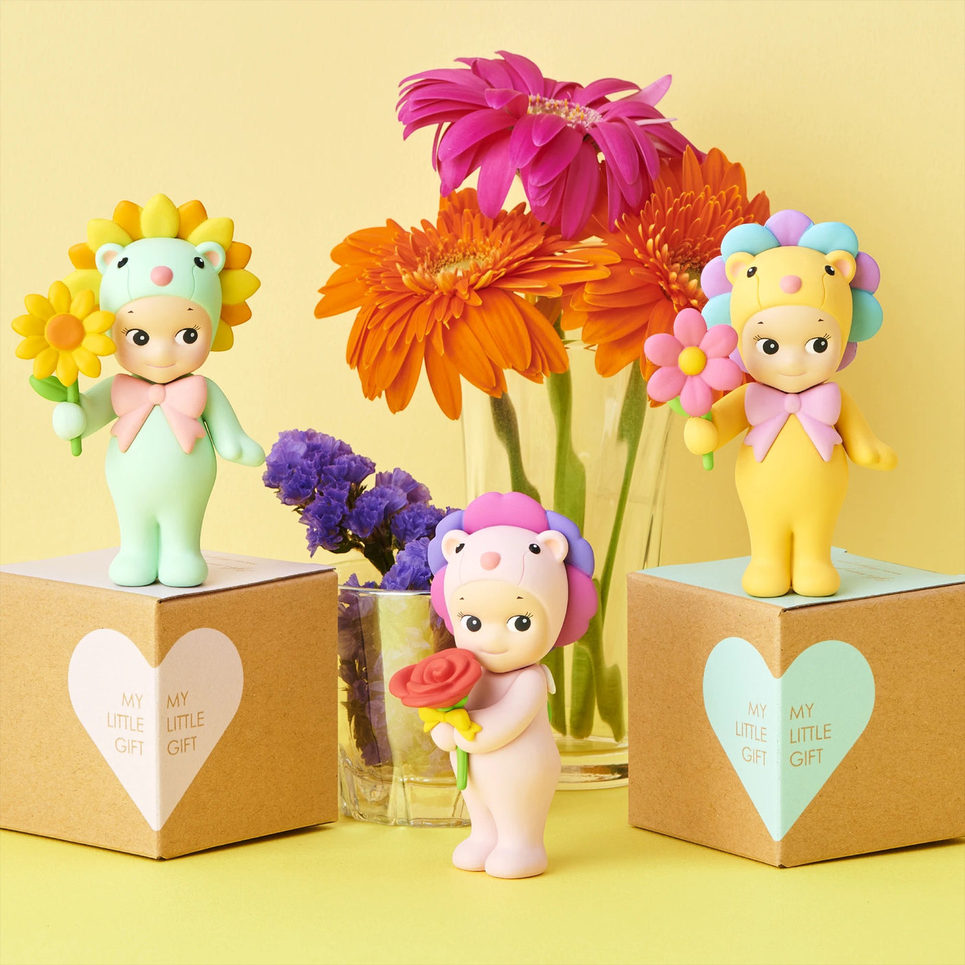 Flower-themed mini figures with flower accessories, posed beside two gift boxes