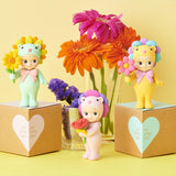 Flower-themed mini figures with flower accessories, posed beside two gift boxes