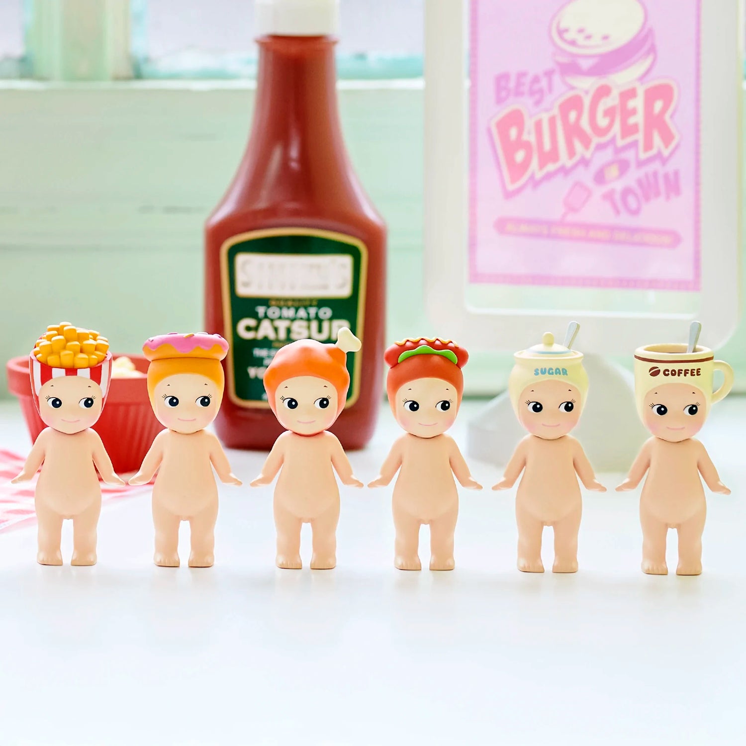 Six Sonny Angel Snack Series - Blind Box mini-figures from Sonny Angel stand in a row, each sporting a unique snack-themed hat. A ketchup bottle and burger sign are in the background. Each figure is a surprise collectible in a blind box.
