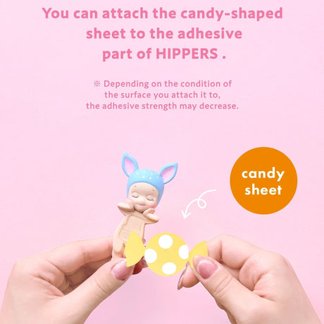 Hands attaching a candy-shaped sheet to a small character figure