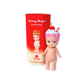 A Sonny Angel Snack Series - Blind Box mini-figure by Sonny Angel, featuring a pink cup and dessert topping on its head, stands beside its red and white blind box packaging.