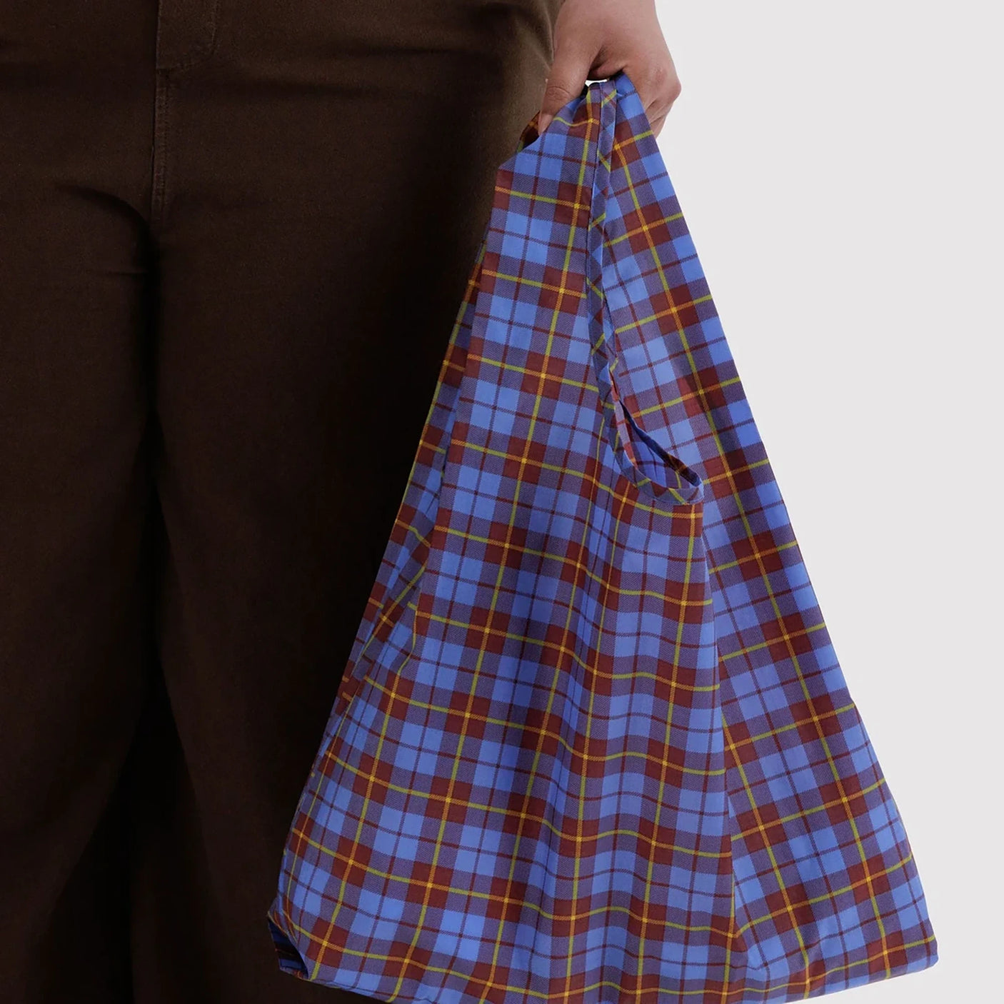 Blue tartan plaid tote bag with drawstring closure, held by the handle.