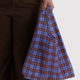 Blue tartan plaid tote bag with drawstring closure, held by the handle.