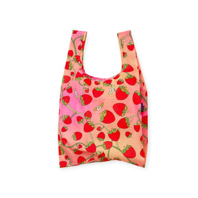 Reusable shopping bag with bright red strawberry pattern on pink and peach gradient background