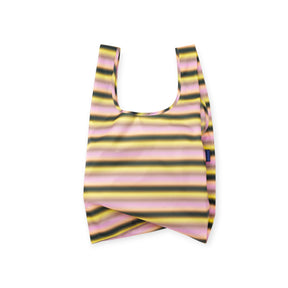 Folded reusable shopping bag with horizontal yellow, black, and pink stripes and fabric tag on side against white background