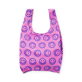 Pink cloth tote bag with repeating smiley face pattern and wide open top.
