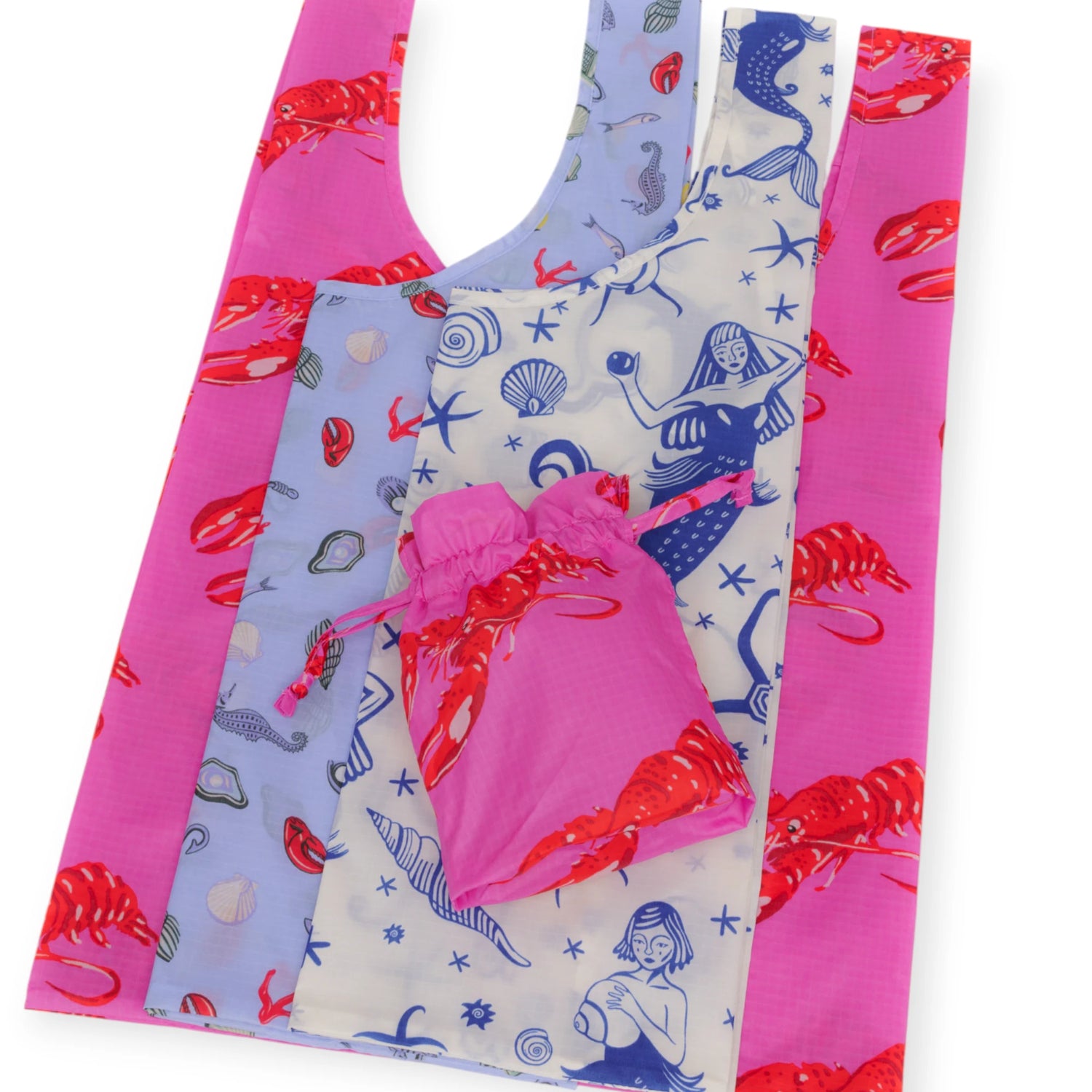 The Baggu Standard Set of 3 - Sea Creatures by Baggu features reusable bags in pink, blue, and white with red lobsters, seashells, and mermaids plus a small pink pouch—stylish and sustainable for all your shopping needs.