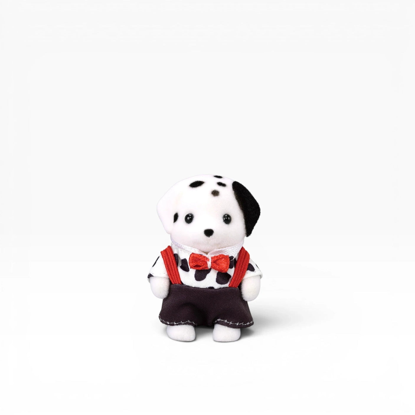 Plush dalmatian doll in dark outfit with red bow tie and red suspenders