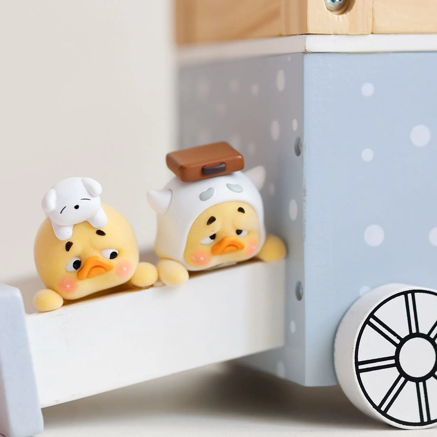 Duck blind box figures seated on shelf ledge, one wearing a white chef hat
