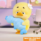Upset Duck Blind Box - Stop The Spiral showing a yellow duck with a white flower hugging a blue fish toy by Upset Duck