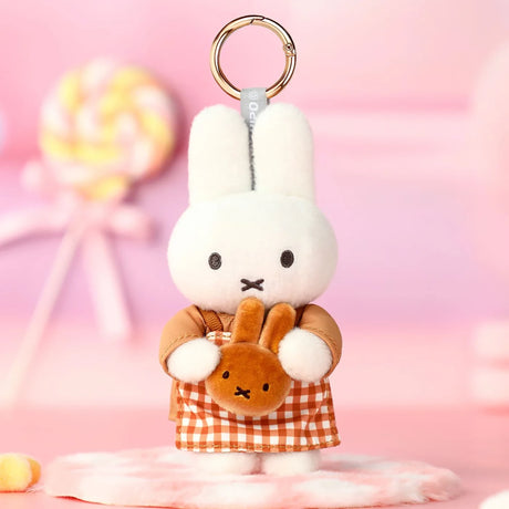 White rabbit plush keychain holding a small brown bear, with orange checkered outfit