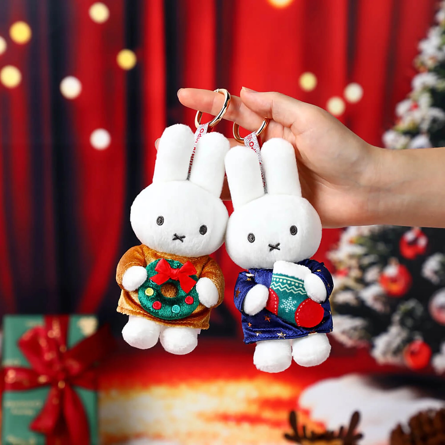 Two Christmas plush keychains: white bunny in tan coat and white bunny in patterned sweater