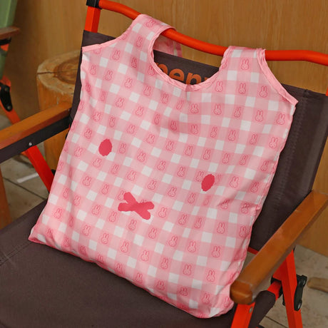Pink miffy tote bag with gingham-style icons, shown folded on a stroller seat