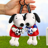 Two Snoopy soccer plush keychains held together, wearing red and blue jerseys with balls