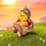 Winnie the Pooh figurine riding a toy vehicle with a honey-carrying drum