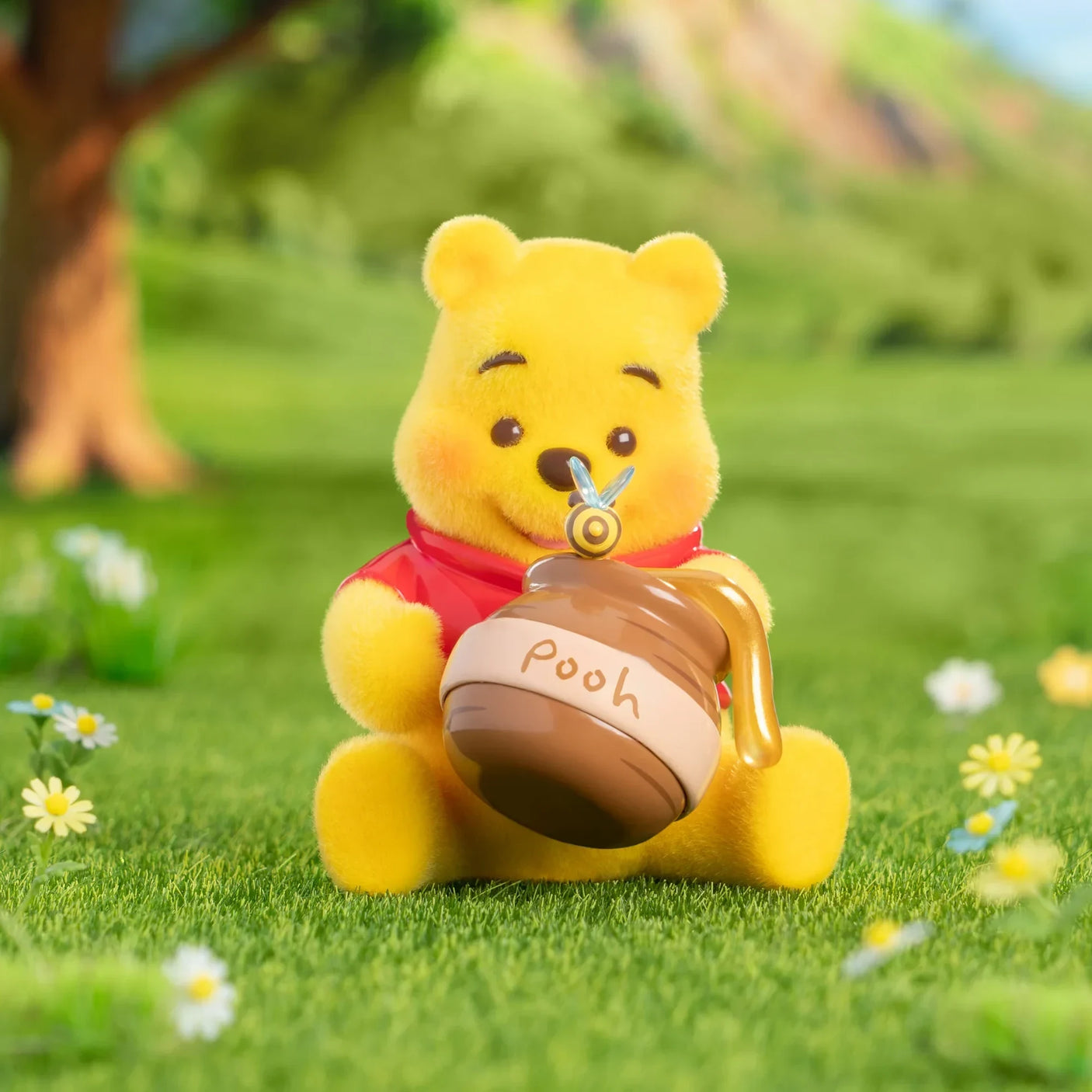 Winnie the Pooh figurine seated on grass holding a honey pot accessory