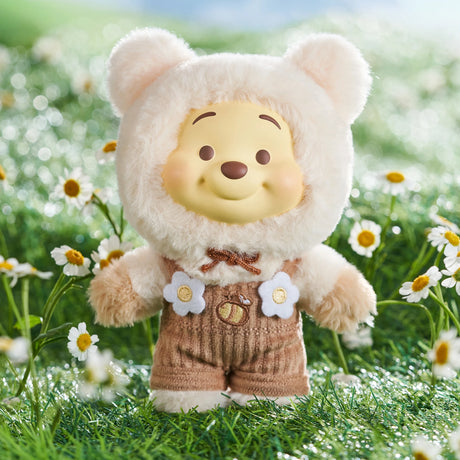 Winnie the Pooh Candy Bear vinyl plush in cream fuzzy bear costume with brown overalls and floral details outdoors on grass