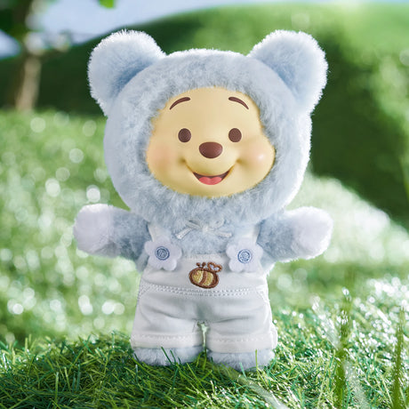 Winnie the Pooh Candy Bear vinyl plush in pale blue fuzzy bear costume with white overalls on grassy background