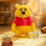 Yellow bear figure in a red shirt with worried face, beside a clear small object