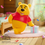 Yellow bear figure in a red shirt running pose, with a gift box beside it