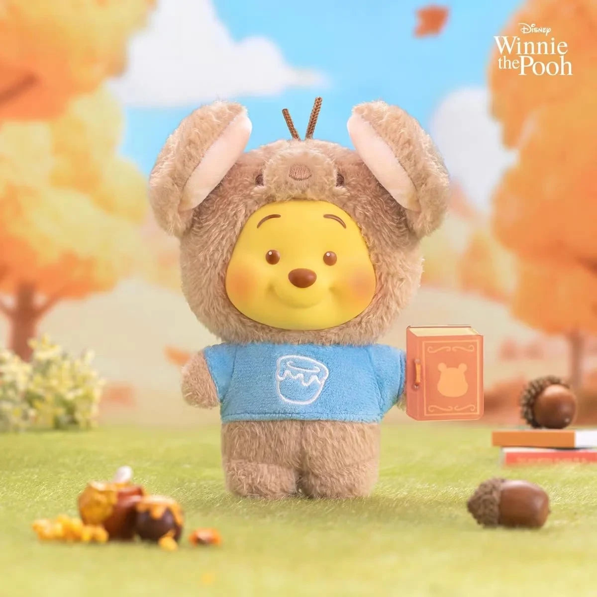 Brown rabbit-eared plush keychain with Pooh face, blue shirt, and orange book tag.
