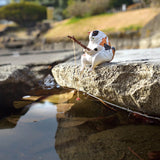 A small bird figurine perches on a rock by the water, holding a thin stick with a string like feline anglers from Yell's Fishing Cats Blind Box - Vol 2.