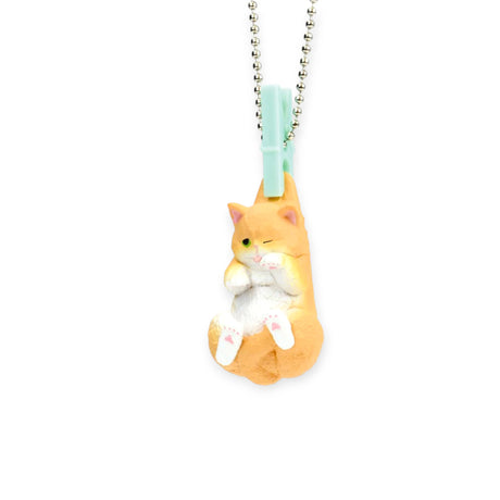 A small, orange and white cat figurine from Yell's Washing Line Critters Charm Blind Box hangs from a light blue clip on a silver beaded chain, shown against a white background.